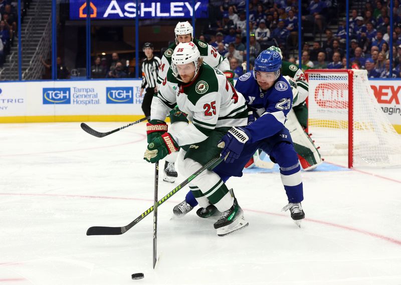 Oct 24, 2024; Tampa, Florida, USA;Minnesota Wild defenseman Jonas Brodin (25) and Tampa Bay Lightning center Michael Eyssimont (23) fight to control the puck  during the third period at Amalie Arena. Mandatory Credit: Kim Klement Neitzel-Imagn Images