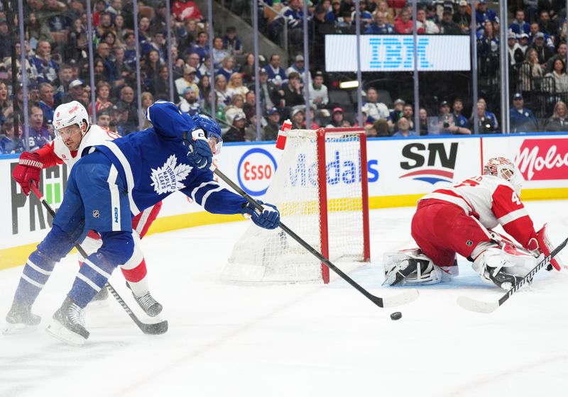 Apr 13, 2024; Toronto, Ontario, CAN; Toronto Maple Leafs center Auston Matthews (34) battles for the puck with Detroit Red Wings defenseman Ben Chiarot (8) during the first period at Scotiabank Arena. Mandatory Credit: Nick Turchiaro-USA TODAY Sports