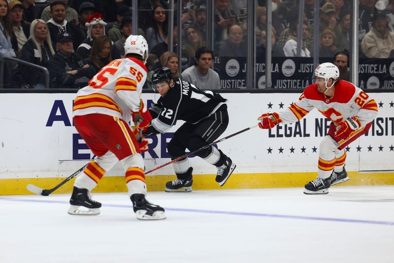 Dec 23, 2023; Los Angeles, California, USA; Los Angeles Kings left wing Trevor Moore (12) skates with the puck against the Calgary Flames during the second period at Crypto.com Arena. Mandatory Credit: Jessica Alcheh-USA TODAY Sports