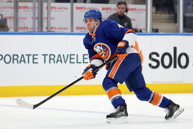 Jan 25, 2025; Elmont, New York, USA; New York Islanders defenseman Tony DeAngelo (4) follows through on a shot against the Carolina Hurricanes during the first period at UBS Arena. Mandatory Credit: Brad Penner-Imagn Images