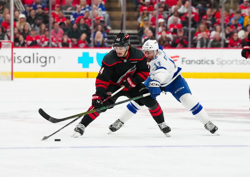 Mar 11, 2025; Raleigh, North Carolina, USA;  Carolina Hurricanes center Seth Jarvis (24) skates with the puck against Tampa Bay Lightning center Luke Glendening (11) during the first period at Lenovo Center. Mandatory Credit: James Guillory-Imagn Images