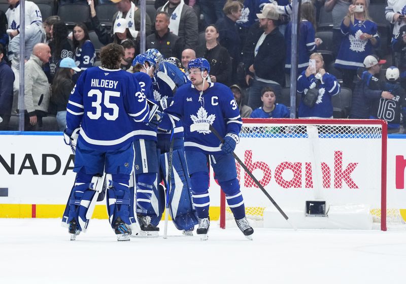 Oct 12, 2024; Toronto, Ontario, CAN; Toronto Maple Leafs center Auston Matthews (34) celebrates the win against the Pittsburgh Penguins with goaltender Dennis Hildeby (35) at the end of the third period at Scotiabank Arena. Mandatory Credit: Nick Turchiaro-Imagn Images