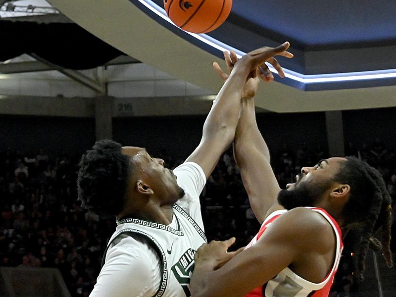 Feb 25, 2024; East Lansing, Michigan, USA;  Michigan State Spartans forward Xavier Booker (34) blocks a shot by Ohio State Buckeyes guard Evan Mahaffey (12) during the first half at Jack Breslin Student Events Center. Mandatory Credit: Dale Young-USA TODAY Sports