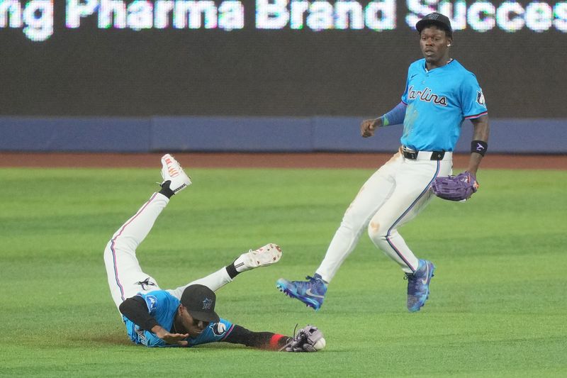 Jul 7, 2024; Miami, Florida, USA;  Miami Marlins left fielder Nick Gordon (1) makes a diving catch as center fielder Jazz Chisholm Jr. (2) backs-up on the play against the Chicago White Sox in the sixth inning at loanDepot Park. Mandatory Credit: Jim Rassol-USA TODAY Sports