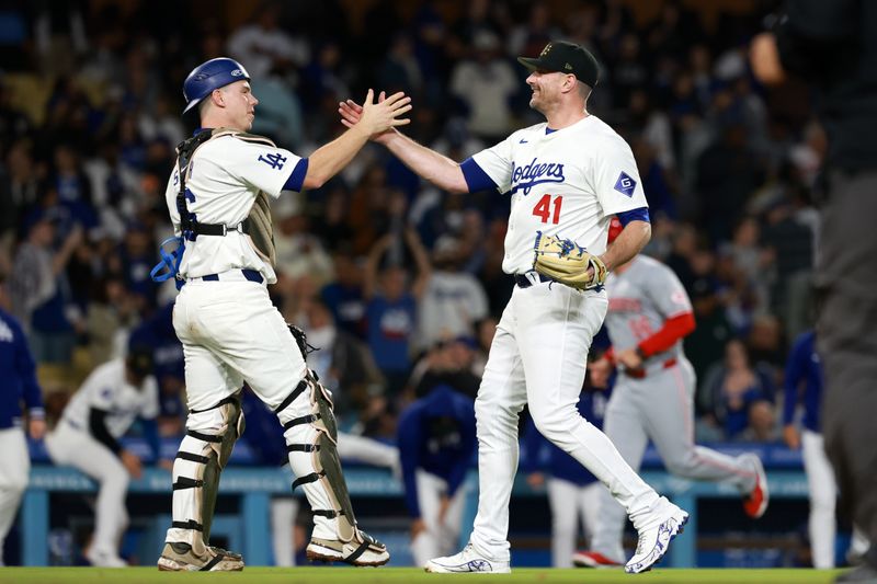 May 17, 2024; Los Angeles, California, USA;  Los Angeles Dodgers catcher Will Smith (16) and relief pitcher Daniel Hudson (41) celebrate a victory after defeating the Cincinnati Reds 7-3 at Dodger Stadium. Mandatory Credit: Kiyoshi Mio-USA TODAY Sports