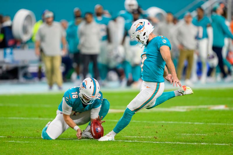 Miami Dolphins punter Jake Bailey (16) holds the ball as Miami Dolphins kicker Jason Sanders (7) kicks for an extra point during an NFL football game against the Tennessee Titans Monday, Dec. 12, 2023, in Miami Gardens, Fla. (AP Photo/Doug Murray)