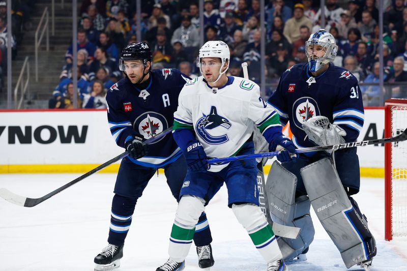 Apr 18, 2024; Winnipeg, Manitoba, CAN;  Winnipeg Jets defenseman Neal Pionk (4) attempts to get in front of Vancouver Canucks forward Nils Hoglander (21) during the first period at Canada Life Centre. Mandatory Credit: Terrence Lee-USA TODAY Sports