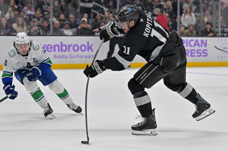Nov 29, 2025; Los Angeles, California, USA; Los Angeles Kings center Anze Kopitar (11) takes a shot on goal as Vancouver Canucks defenseman Quinn Hughes (43) defends during the overtime period at Crypto.com Arena. Mandatory Credit: Jayne Kamin-Oncea-Imagn Images