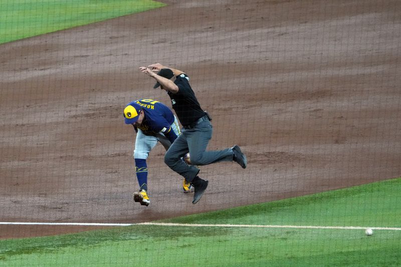 Sep 13, 2024; Phoenix, Arizona, USA; FIrst base umpire Tripp Gibson (73) jumps out of the way of the ball as Milwaukee Brewers first base Rhys Hoskins (12) cannot make a play during the fourth inning at Chase Field. Mandatory Credit: Joe Camporeale-Imagn Images