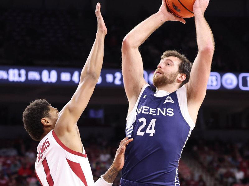 Dec 16, 2025; Fayetteville, Arkansas, USA; Queens Royals guard Yoav Berman (24) shoots as Arkansas Razorbacks guard Meleek Thomas (1) defends during the first half at Bud Walton Arena. Mandatory Credit: Nelson Chenault-Imagn Images