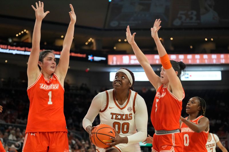 Dec 29, 2024; Austin, Texas, USA; Texas Longhorns center Kyla Oldacre (00) drives to the basket between Rio Grande Valley Vaqueros forward Charlotte O'Keefe (1) and guard  and Kade Hackeroff (5) during the first half at Moody Center. Mandatory Credit: Scott Wachter-Imagn Images
