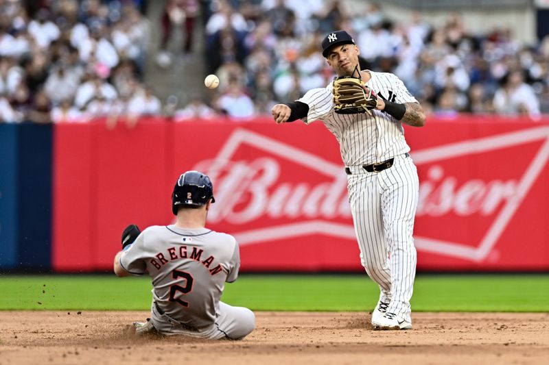 May 9, 2024; Bronx, New York, USA; New York Yankees second baseman Gleyber Torres (25) gets a force out at second base on Houston Astros third baseman Alex Bregman (2) and throws to first base to complete a double play during the sixth inning at Yankee Stadium. Mandatory Credit: John Jones-USA TODAY Sports