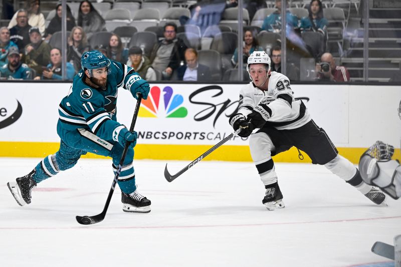 Oct 29, 2024; San Jose, California, USA; San Jose Sharks center Luke Kunin (11) takes a shot on goal against Los Angeles Kings defenseman Brandt Clarke (92) in the second period at SAP Center at San Jose. Mandatory Credit: Eakin Howard-Imagn Images