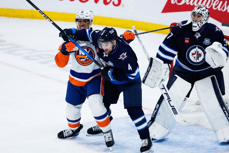 Jan 13, 2026; Winnipeg, Manitoba, CAN;  Winnipeg Jets defenseman Neal Pionk (4) battles with New York Islanders forward Anthony Duclair (11) during the third period at Canada Life Centre. Mandatory Credit: Terrence Lee-Imagn Images