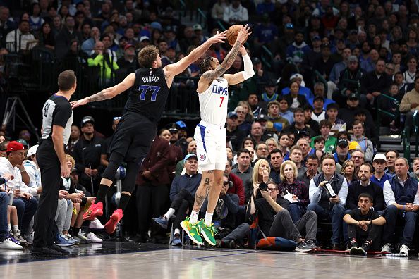 DALLAS, TEXAS - DECEMBER 20: Amir Coffey #7 of the LA Clippers shoots the ball as Luka Doncic #77 of the Dallas Mavericks attempts to block his shot in the first half at American Airlines Center on December 20, 2023 in Dallas, Texas. NOTE TO USER: User expressly acknowledges and agrees that, by downloading and or using this photograph, User is consenting to the terms and conditions of the Getty Images License Agreement. (Photo by Tim Heitman/Getty Images)