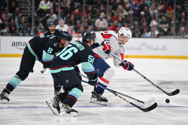 Mar 14, 2024; Seattle, Washington, USA; Washington Capitals center Connor McMichael (24) plays the puck while defended by Seattle Kraken defenseman Brian Dumoulin (8) and Seattle Kraken right wing Kailer Yamamoto (56) during the third period at Climate Pledge Arena. Mandatory Credit: Steven Bisig-USA TODAY Sports