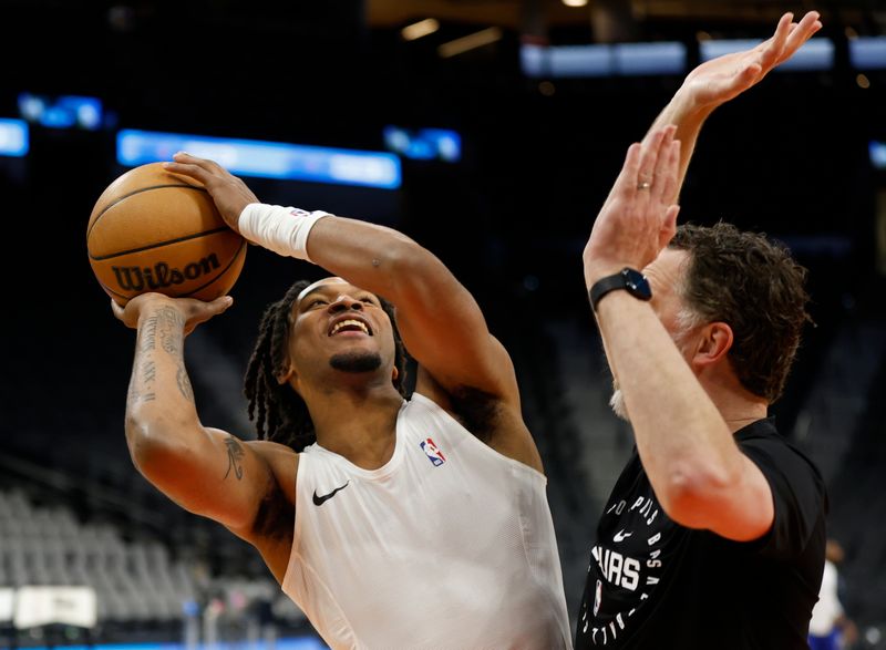 SAN ANTONIO, TX - MARCH 21:  Stephon Castle #5 of the San Antonio Spurs shots around Matt Nielsen assistant coach before their game against the Philadelphia 76ers at Frost Bank Center on March 21, 2025 in San Antonio, Texas. NOTE TO USER: User expressly acknowledges and agrees that, by downloading and or using this photograph, User is consenting to terms and conditions of the Getty Images License Agreement. (Photo by Ronald Cortes/Getty Images)