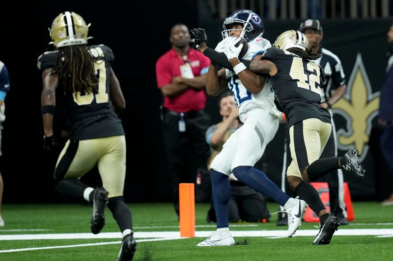 Tennessee Titans wide receiver Bryce Oliver scores in front of New Orleans Saints cornerback Mac McCain III during the second half of an NFL preseason football game, Sunday, Aug. 25, 2024, in New Orleans. (AP Photo/Gerald Herbert)