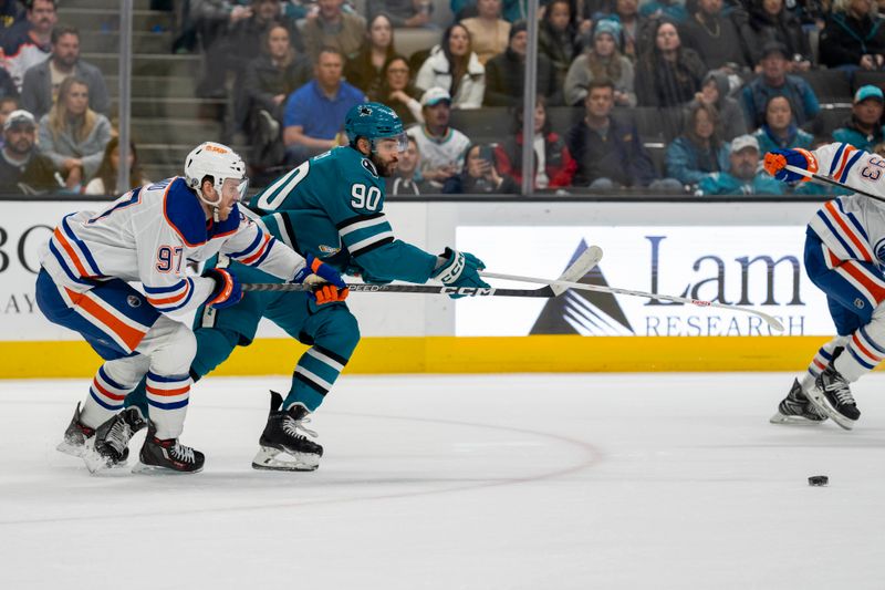 Dec 28, 2023; San Jose, California, USA; San Jose Sharks right wing Justin Bailey (90) passes the puck against Edmonton Oilers center Connor McDavid (97) during the first period at SAP Center at San Jose. Mandatory Credit: Neville E. Guard-USA TODAY Sports