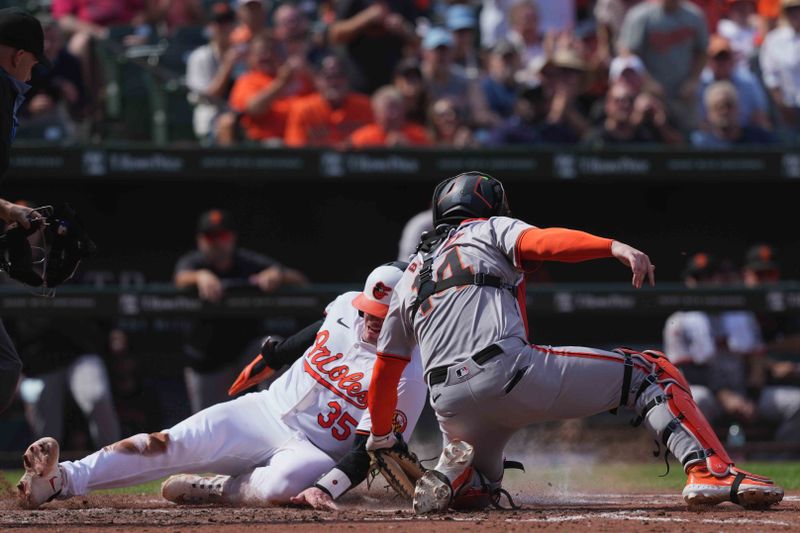 Sep 19, 2024; Baltimore, Maryland, USA; Baltimore Orioles catcher Adley Rutschman (35) scores ahead of a tag by San Francisco Giants catcher Patrick Bailey (14) in the fourth inning at Oriole Park at Camden Yards. Mandatory Credit: Mitch Stringer-Imagn Images