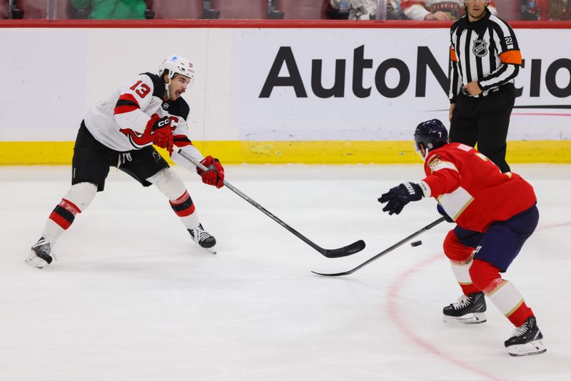 Nov 12, 2024; Sunrise, Florida, USA; New Jersey Devils center Nico Hischier (13) moves the puck as Florida Panthers defenseman Dmitry Kulikov (7) defends during the third period at Amerant Bank Arena. Mandatory Credit: Sam Navarro-Imagn Images