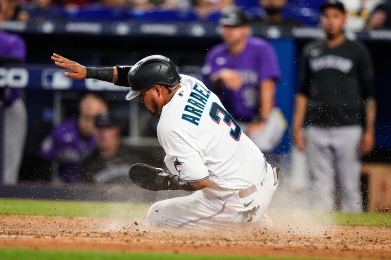 Jul 23, 2023; Miami, Florida, USA; Miami Marlins second baseman Luis Arraez (3) slides into home base against the Colorado Rockies during the sixth inning at loanDepot Park. Mandatory Credit: Rich Storry-USA TODAY Sports