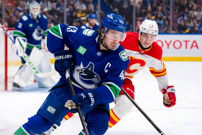 Oct 9, 2024; Vancouver, British Columbia, CAN; Vancouver Canucks defenseman Quinn Hughes (43) drives past Calgary Flames forward Samuel Honzek (29) during the third period at Rogers Arena. Mandatory Credit: Bob Frid-Imagn Images