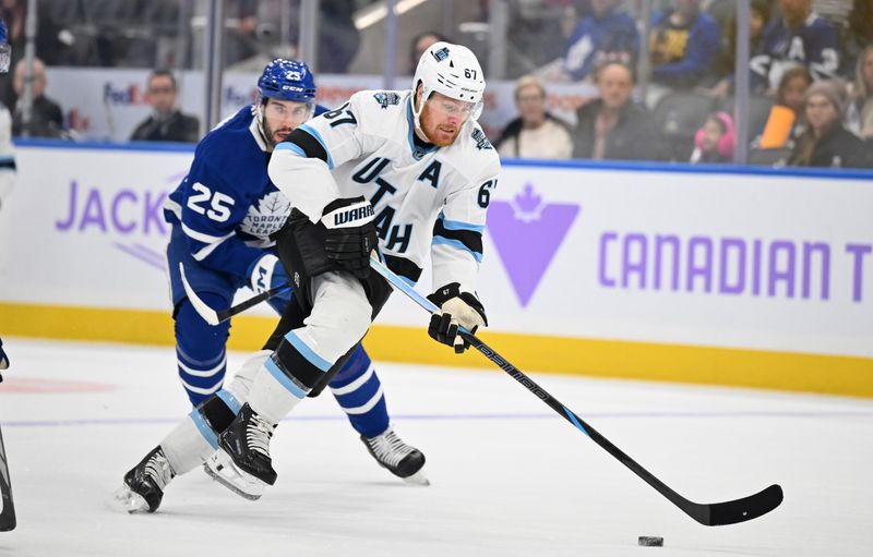 Nov 24, 2024; Toronto, Ontario, CAN;  Utah Hockey Club forward Lawson Crouse (67) breaks past Toronto Maple Leafs defenseman Conor Timmins (25) in the second period at Scotiabank Arena. Mandatory Credit: Dan Hamilton-Imagn Images