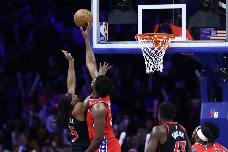 PHILADELPHIA, PENNSYLVANIA - DECEMBER 22: Joel Embiid #21 of the Philadelphia 76ers blocks Precious Achiuwa #5 of the Toronto Raptors during the third quarter at the Wells Fargo Center on December 22, 2023 in Philadelphia, Pennsylvania. NOTE TO USER: User expressly acknowledges and agrees that, by downloading and or using this photograph, User is consenting to the terms and conditions of the Getty Images License Agreement. (Photo by Tim Nwachukwu/Getty Images)