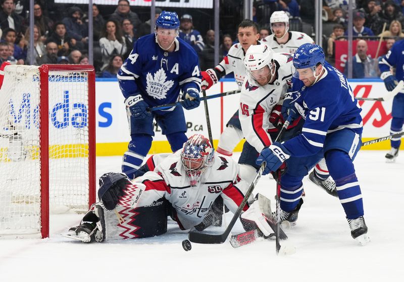 Dec 6, 2024; Toronto, Ontario, CAN; Toronto Maple Leafs center John Tavares (91) battles for the puck with Washington Capitals right wing Taylor Raddysh (16) in front of goaltender Charlie Lindgren (79) during the third period at Scotiabank Arena. Mandatory Credit: Nick Turchiaro-Imagn Images