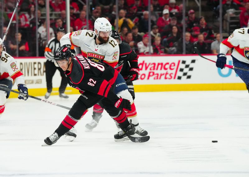 Mar 14, 2024; Raleigh, North Carolina, USA; Carolina Hurricanes center Jesperi Kotkaniemi (82) and Florida Panthers left wing Jonah Gadjovich (12) battle over the puck during the first period at PNC Arena. Mandatory Credit: James Guillory-USA TODAY Sports