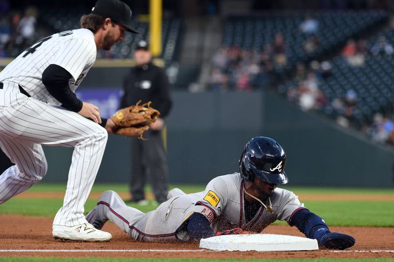 Apr 29, 2025; Denver, Colorado, USA; Atlanta Braves second base Ozzie Albies (1) slides into third base ahead of a tag by Colorado Rockies third base Ryan McMahon (24) during the fifth inning at Coors Field. Mandatory Credit: Christopher Hanewinckel-Imagn Images