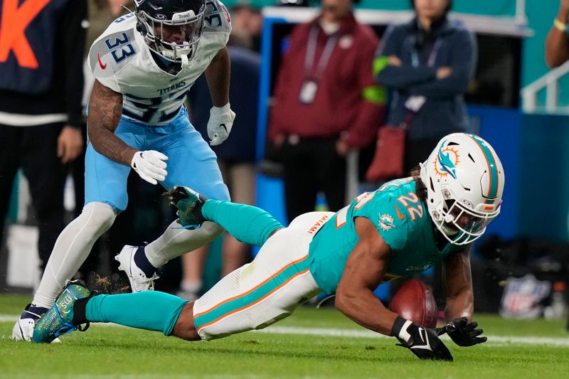 Miami Dolphins safety Elijah Campbell (22) recovers a fumble by Tennessee Titans cornerback Eric Garror (33) during the second half of an NFL football game, Monday, Dec. 11, 2023, in Miami. (AP Photo/Lynne Sladky)