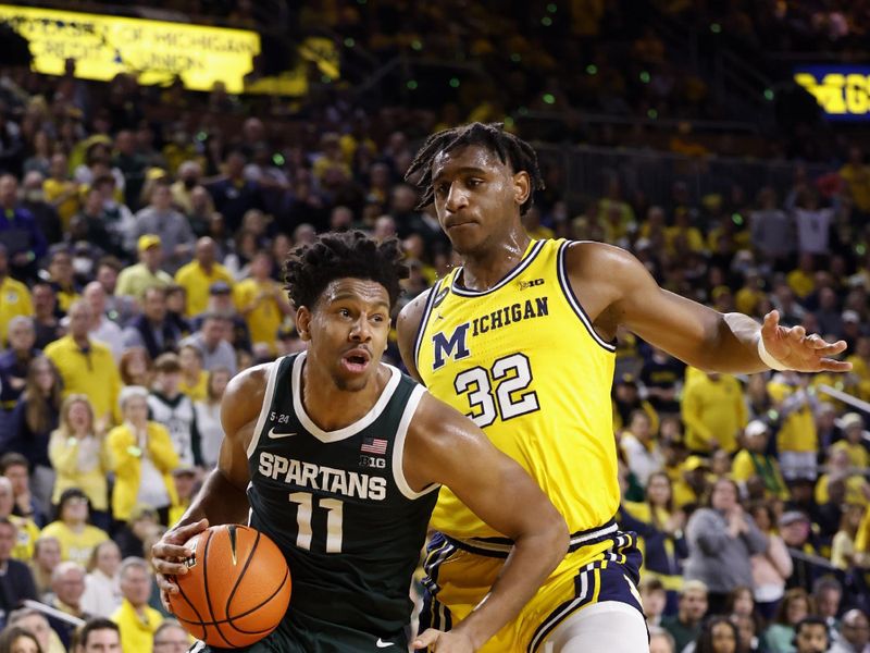 Feb 18, 2023; Ann Arbor, Michigan, USA;  Michigan State Spartans guard A.J. Hoggard (11) dribbles the ball against Michigan Wolverines forward Tarris Reed Jr. (32) in the second half at Crisler Center. Mandatory Credit: Rick Osentoski-USA TODAY Sports