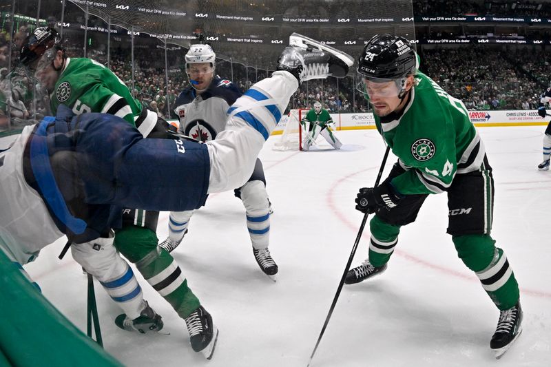 Apr 10, 2025; Dallas, Texas, USA; Dallas Stars center Roope Hintz (24) is nearly hit by the skate blade of Winnipeg Jets center Adam Lowry (17) as Lowry is checked by defenseman Lian Bichsel (6) during the first period at the American Airlines Center. Mandatory Credit: Jerome Miron-Imagn Images