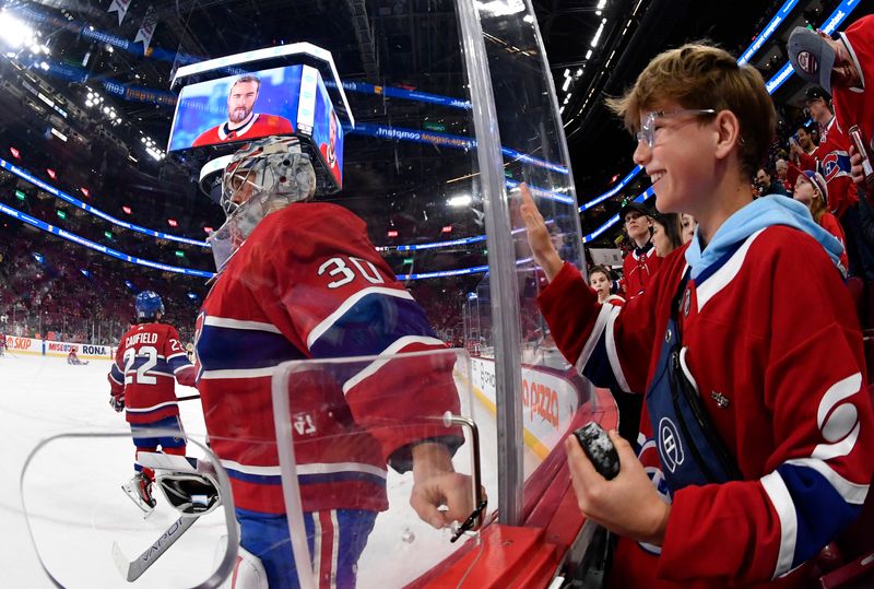 Mar 14, 2024; Montreal, Quebec, CAN; Montreal Canadiens goalie Cayden Primeau (30) gives a puck to a young fan during the warmup period before the game against the Boston Bruins at the Bell Centre. Mandatory Credit: Eric Bolte-USA TODAY Sports