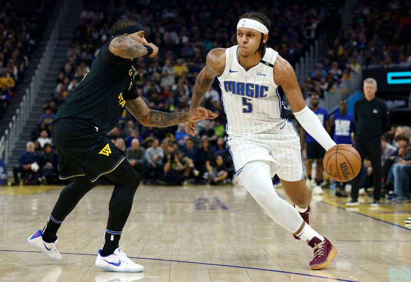 SAN FRANCISCO, CALIFORNIA - FEBRUARY 03: Paolo Banchero #5 of the Orlando Magic dribbling the ball is guarded by Gary Payton II #0 of the Golden State Warriors during the first half of an NBA basketball game at Chase Center on February 03, 2025 in San Francisco, California. NOTE TO USER: User expressly acknowledges and agrees that, by downloading and or using this photograph, User is consenting to the terms and conditions of the Getty Images License Agreement.  (Photo by Thearon W. Henderson/Getty Images)