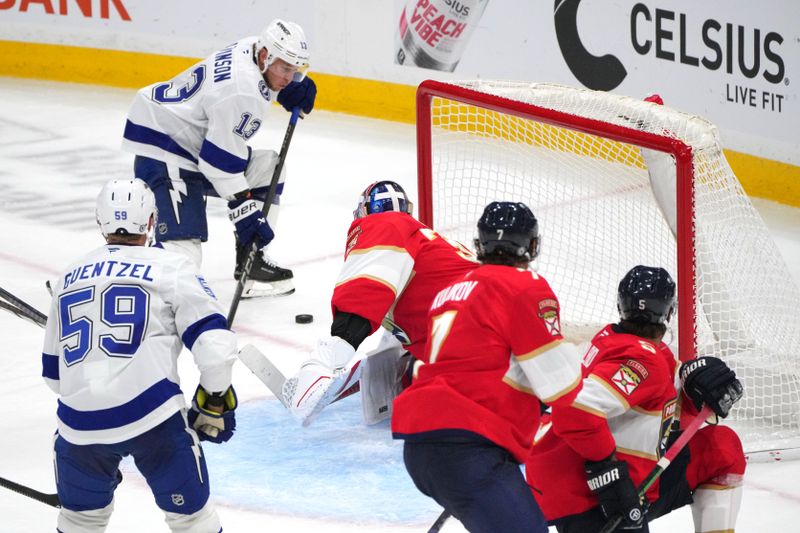 Sep 30, 2024; Sunrise, Florida, USA; Florida Panthers goaltender Spencer Knight (30) sends the puck wide as Tampa Bay Lightning right wing Cameron Atkinson (13) closes in during the third period at Amerant Bank Arena. Mandatory Credit: Jim Rassol-Imagn Images