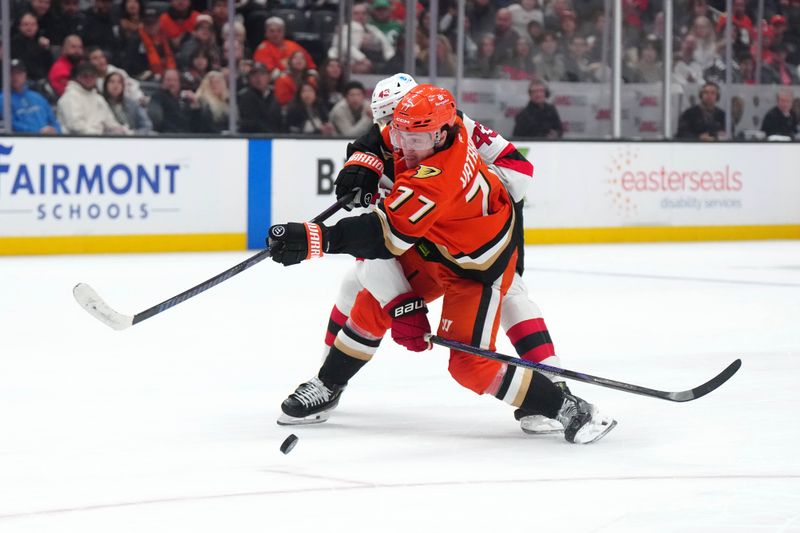Dec 31, 2024; Anaheim, California, USA; Anaheim Ducks right wing Frank Vatrano (77) shoots the puck against New Jersey Devils defenseman Luke Hughes (43) in the third period at Honda Center. Mandatory Credit: Kirby Lee-Imagn Images