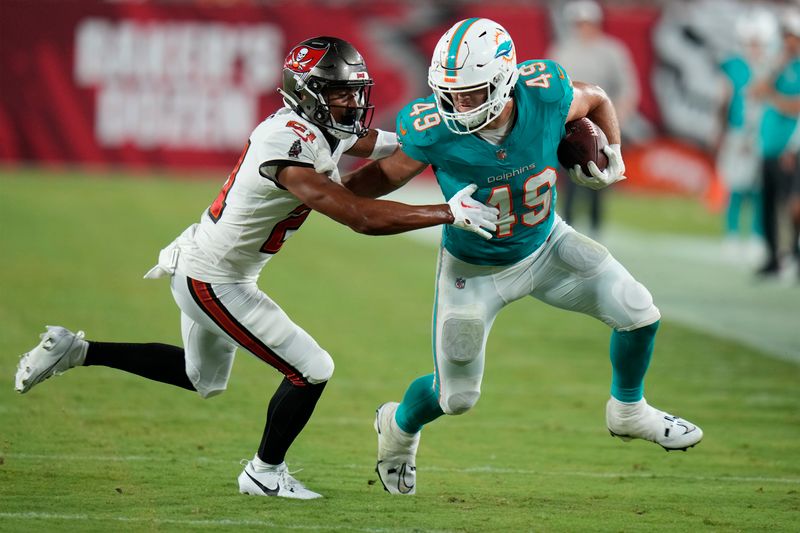 Tampa Bay Buccaneers cornerback Andrew Hayes (21) attempts to stop Miami Dolphins tight end Hayden Rucci (49) during the second half of a pre season NFL football game, Friday, Aug. 23, 2024, in Tampa, Fla. (AP Photo/Chris O'Meara)