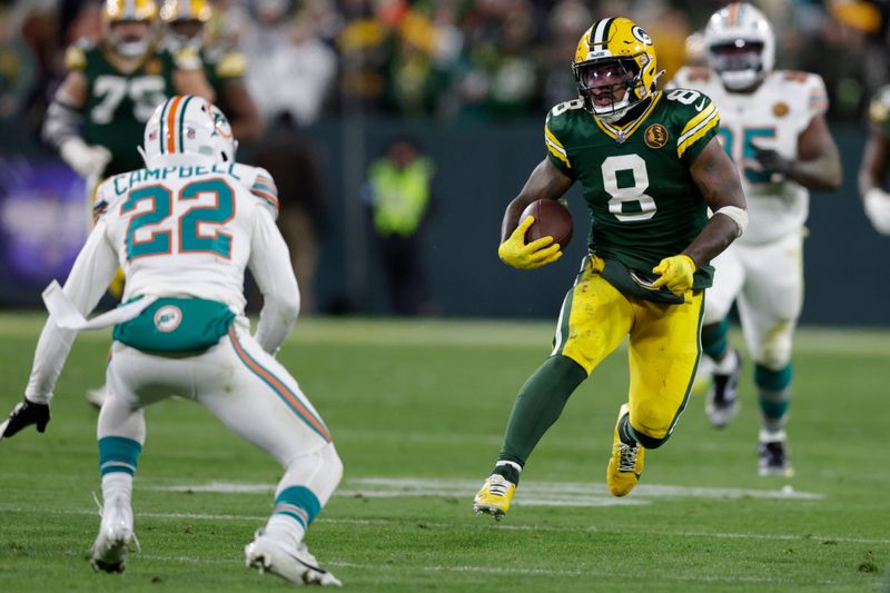 Green Bay Packers running back Josh Jacobs (8) runs from Miami Dolphins safety Elijah Campbell (22) during the second half of an NFL football game Thursday, Nov. 28, 2024, in Green Bay, Wis. (AP Photo/Matt Ludtke)