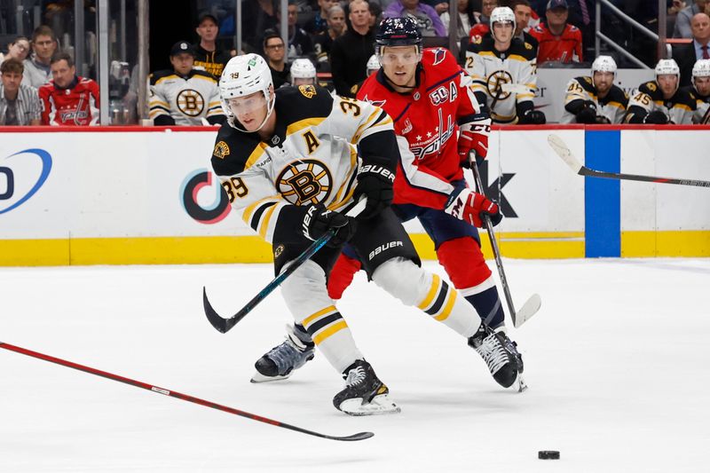 Oct 5, 2024; Washington, District of Columbia, USA; Boston Bruins center Morgan Geekie (39) passes the puck as Washington Capitals defenseman John Carlson (74) chases in the second period at Capital One Arena. Mandatory Credit: Geoff Burke-Imagn Images