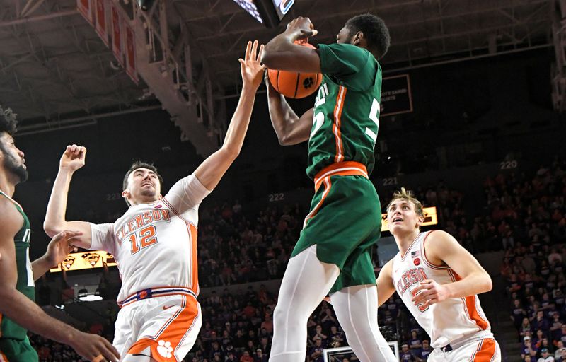 Feb 4, 2023; Clemson, South Carolina, USA; Miami guard Wooga Poplar (55) rebounds near Clemson senior guard Alex Hemenway (12) and Clemson forward Hunter Tyson (5) during the second half at Littlejohn Coliseum in Clemson, S.C. Saturday, Feb. 4, 2023. Mandatory Credit: Ken Ruinard-USA TODAY Sports