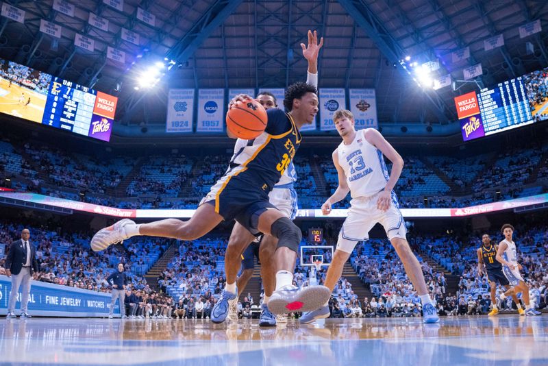 Dec 16, 2025; Chapel Hill, North Carolina, USA; ETSU Buccaneers forward Jordan McCullum (35) drives to the basket past North Carolina Tar Heels forward Jarin Stevenson (15) and center Henri Veesaar (13) during the first half at Dean E. Smith Center. Mandatory Credit: Scott Kinser-Imagn Images