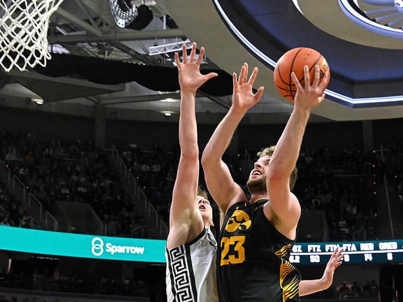 Feb 20, 2024; East Lansing, Michigan, USA;  Michigan State Spartans forward Jaxon Kohler (0) defends Iowa Hawkeyes forward Ben Krikke (23) during the first half at Jack Breslin Student Events Center. Mandatory Credit: Dale Young-USA TODAY Sports
