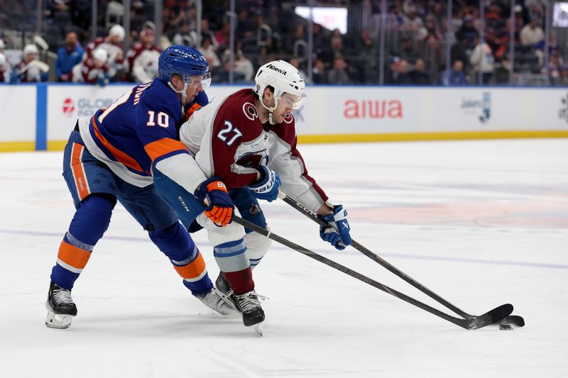 Jan 28, 2025; Elmont, New York, USA; New York Islanders right wing Simon Holmstrom (10) and Colorado Avalanche left wing Jonathan Drouin (27) fight for the puck during the third period at UBS Arena. Mandatory Credit: Brad Penner-Imagn Images