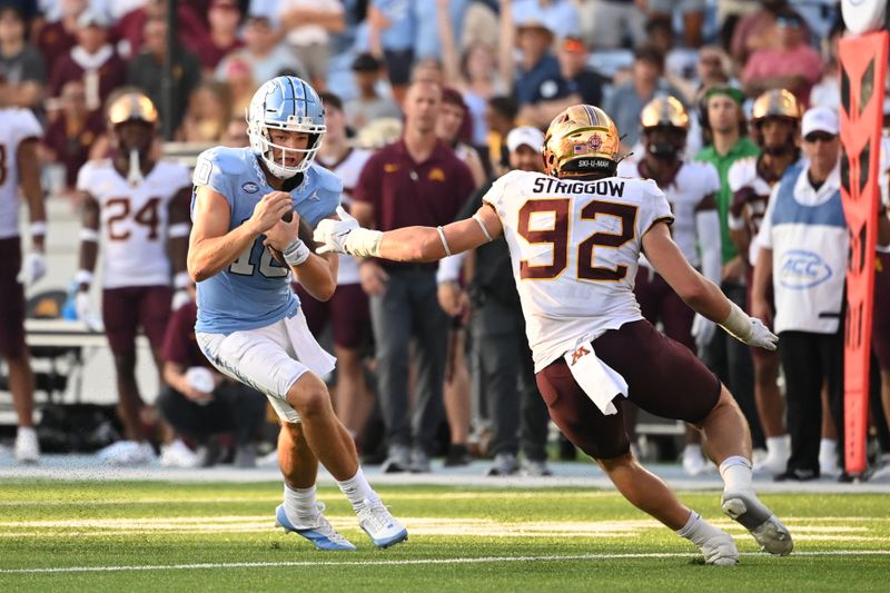 Sep 16, 2023; Chapel Hill, North Carolina, USA;  North Carolina Tar Heels quarterback Drake Maye (10) with the ball as Minnesota Golden Gophers defensive lineman Danny Striggow (92) defends in the fourth quarter at Kenan Memorial Stadium. Mandatory Credit: Bob Donnan-USA TODAY Sports