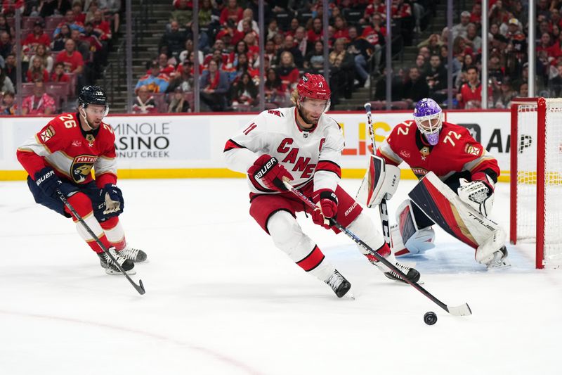 Nov 10, 2023; Sunrise, Florida, USA; Carolina Hurricanes center Jordan Staal (11) plays the puck in front of Florida Panthers defenseman Uvis Balinskis (26) and goaltender Sergei Bobrovsky (72) during the first period at Amerant Bank Arena. Mandatory Credit: Jasen Vinlove-USA TODAY Sports