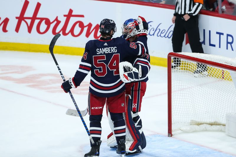 Dec 22, 2023; Winnipeg, Manitoba, CAN;  Winnipeg Jets goalie Connor Hellebuyck (37) is congratulated by  defenseman Dylan Samberg (54) on his win against the Boston Bruins during the third period at Canada Life Centre. Mandatory Credit: Terrence Lee-USA TODAY Sports