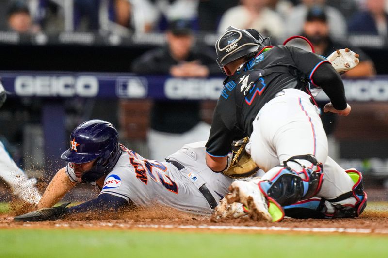 Aug 16, 2023; Miami, Florida, USA; Houston Astros center fielder Chas McCormick (20) slides into home base to score as Miami Marlins catcher Nick Fortes (4) attempts a tag during the seventh inning at loanDepot Park. Mandatory Credit: Rich Storry-USA TODAY Sports